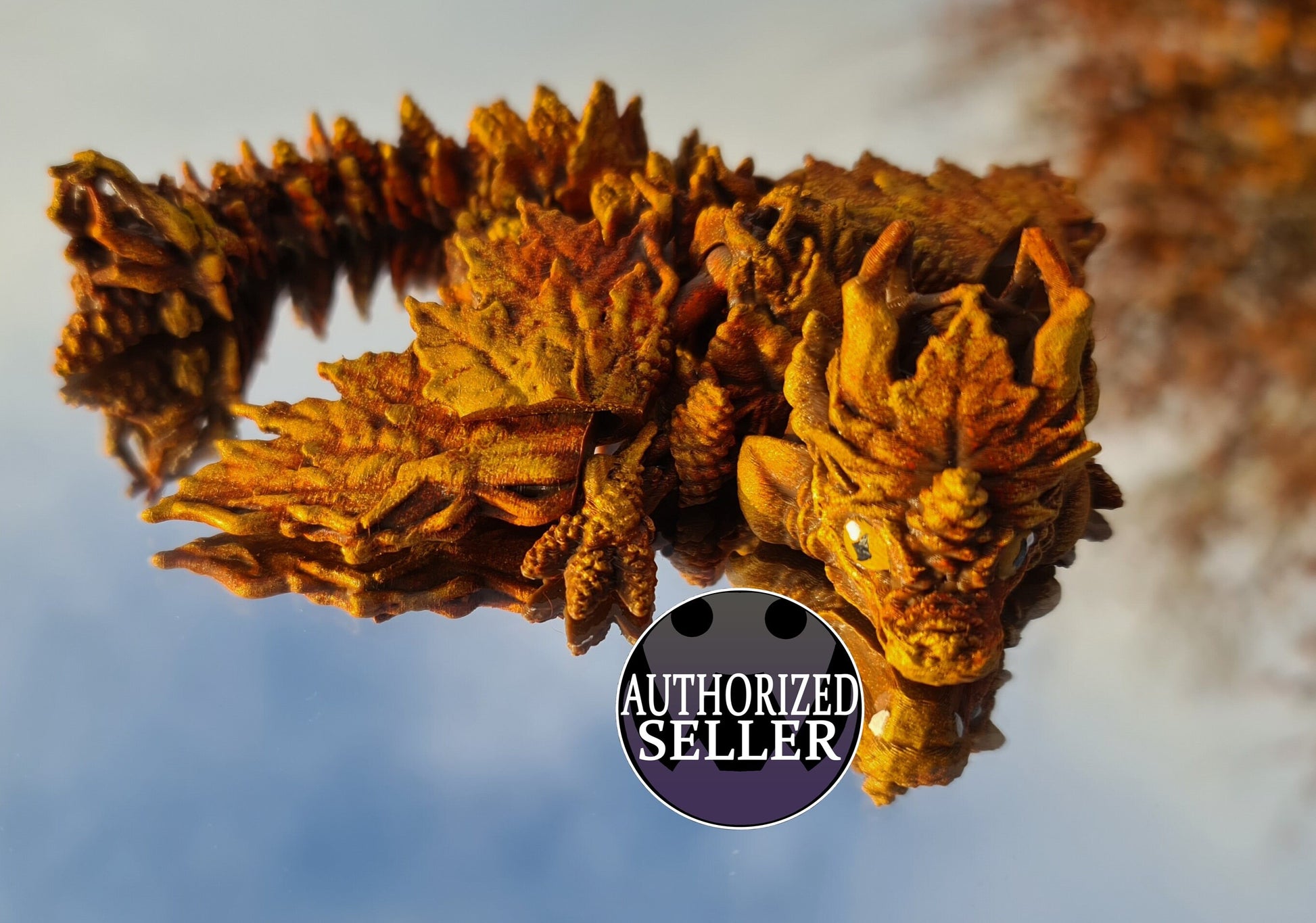 3D printed autumn leaf dragon figurine on reflective surface, Authorized Seller badge visible