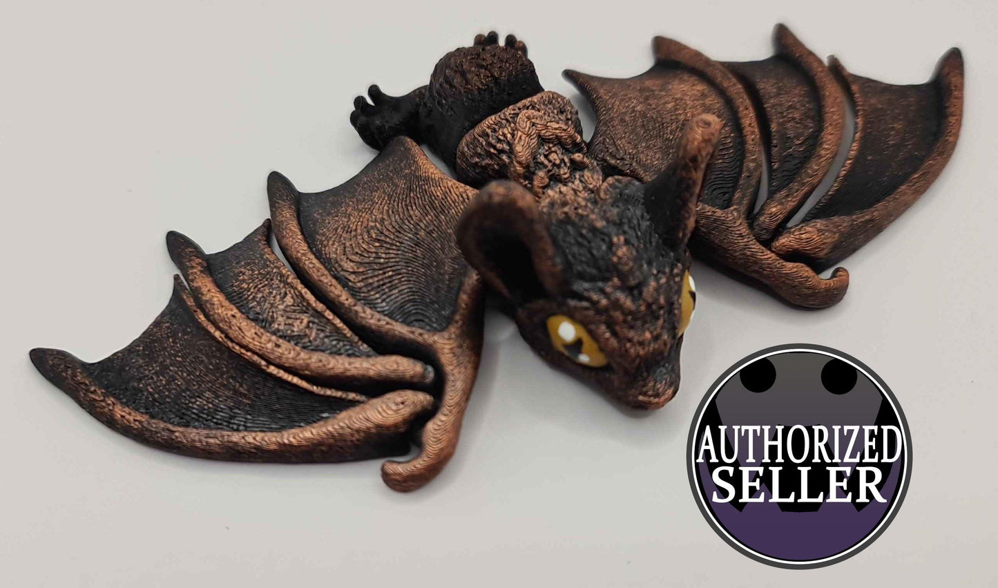 Handmade black and bronze bat figurine with yellow eyes and Authorized Seller badge