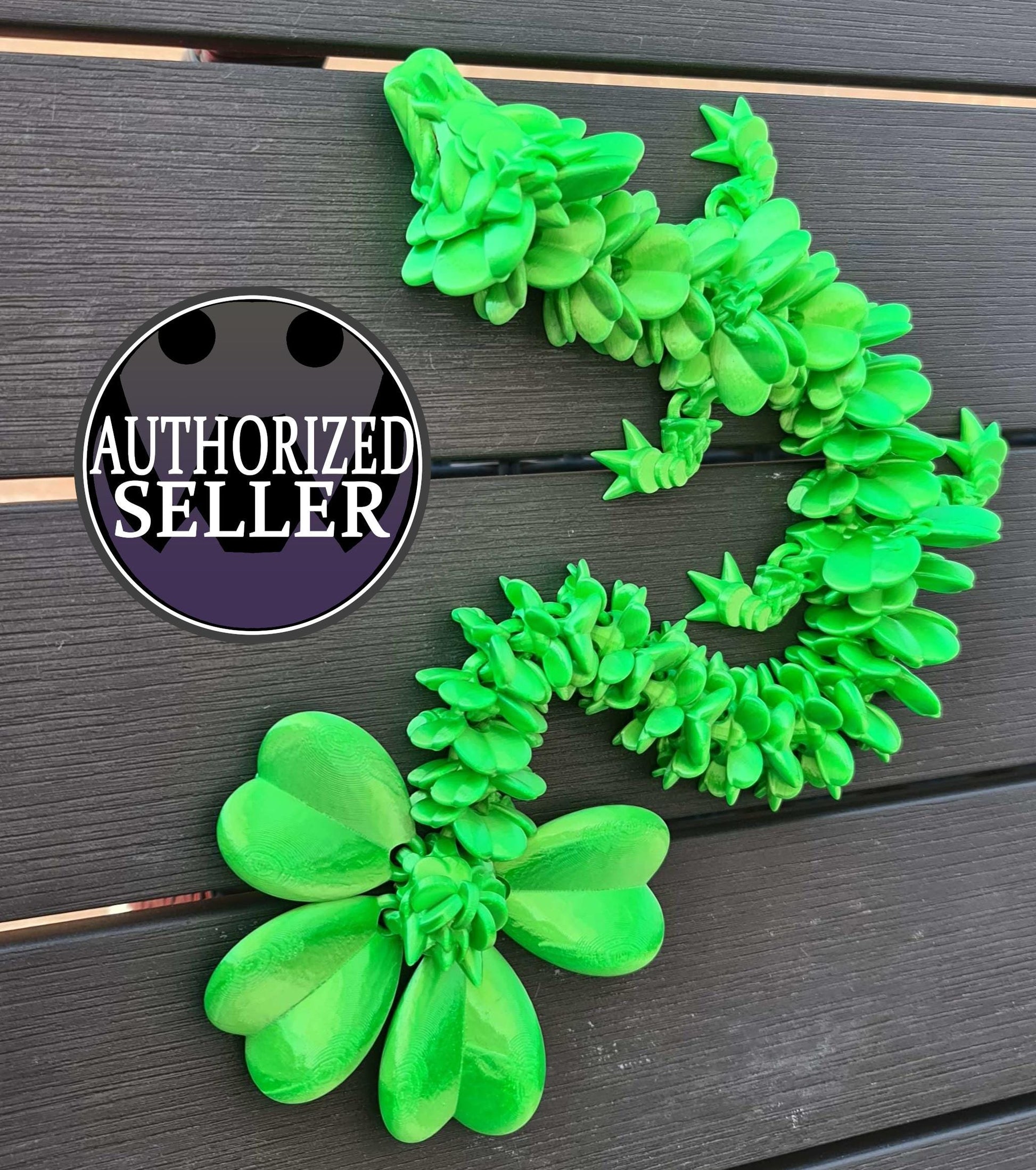 Green 3D printed succulent lizard on dark wood, authorized seller badge at left