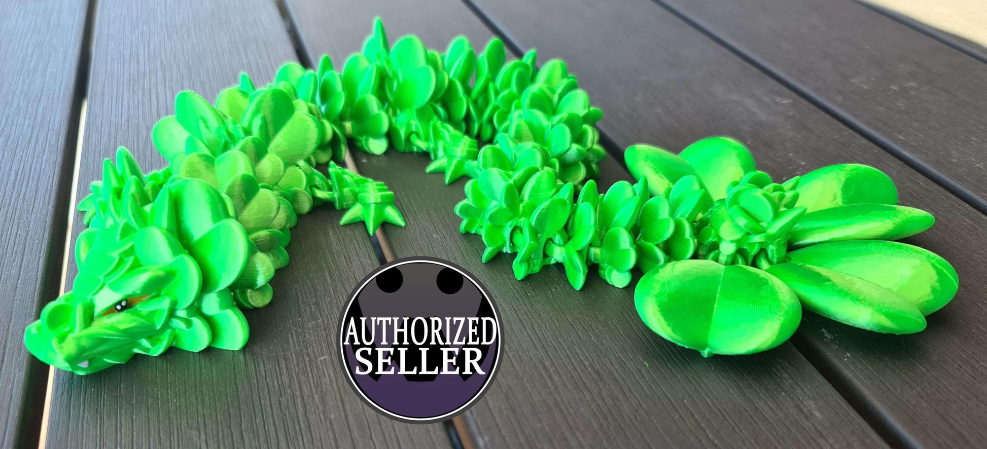 Green 3D printed dragon with succulent-like scales on dark wood, authorized seller badge