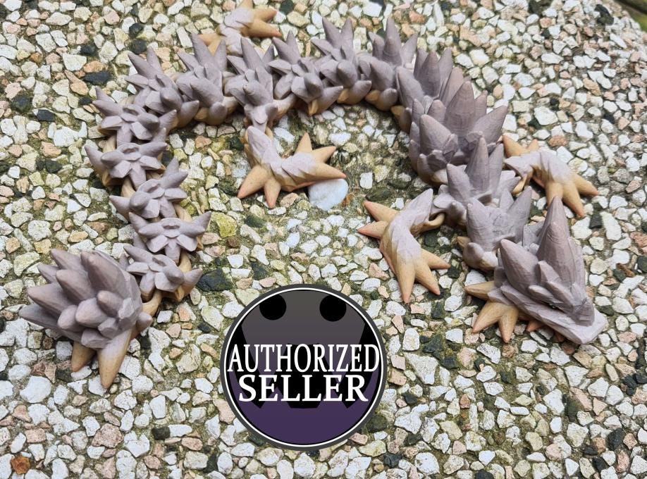 Articulated wooden spiked dragon figurine on pebble surface, authorized seller badge.