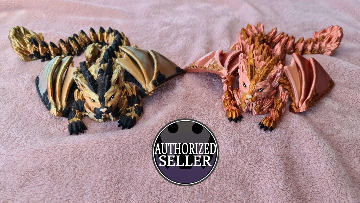 Two detailed dragon figurines on pink fabric, black and gold, pink and gold, authorized seller badge